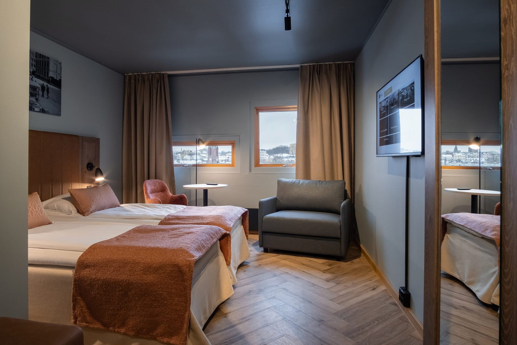 Twin room with armchair and mirrored wall